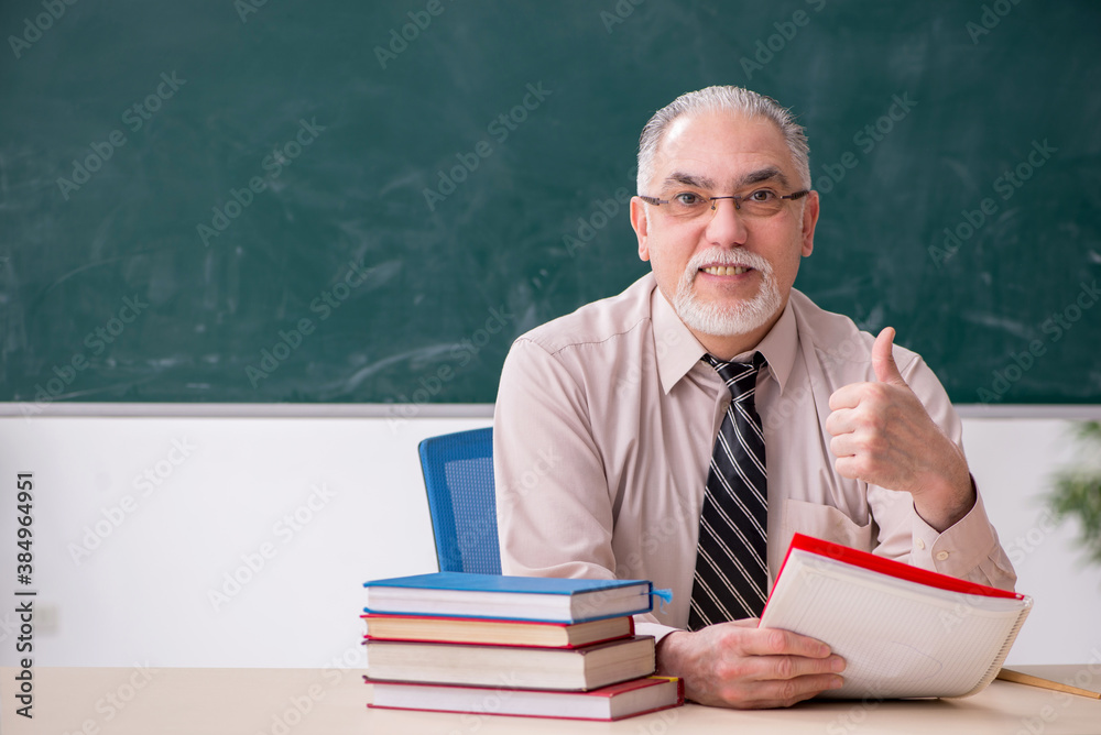 Old male teacher in the classroom Old male teacher in the classroom