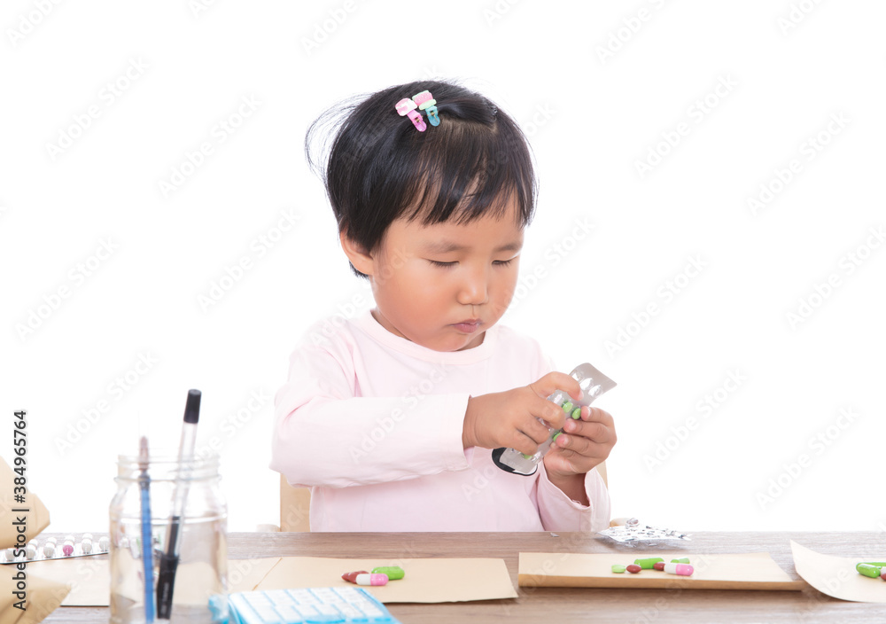 A little girl who plays a pharmacist in front of a white background is simulating dispensing medicine A little girl who plays a pharmacist in front of a white background is simulating dispensing medicine