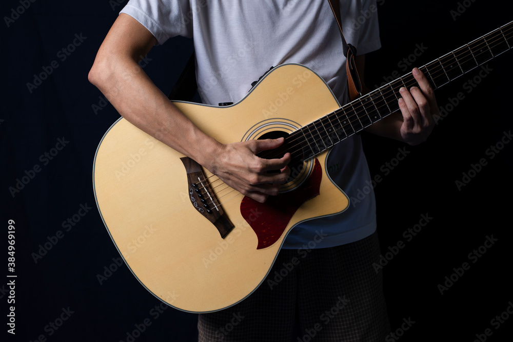Fototapeta premium Musician playing acoustic guitar in the dark, At night with side lighting