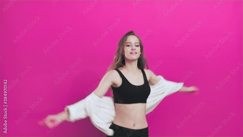 Young Woman Having Fun Smiling Dancing in Studio Shaking Her Hair While Listening to Music Against Pink Background. Energetic Dancing of a Happy Teenage Girl Slow Motion Young Woman Having Fun Smiling Dancing in Studio Shaking Her Hair While Listening to Music Against Pink Background. Energetic Dancing of a Happy Teenage Girl Slow Motion