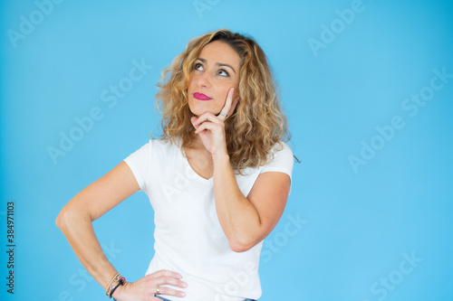 happy young woman thinking over blue background.