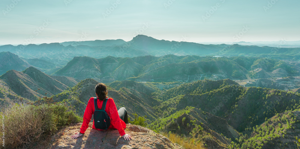 Obraz premium Young woman sittting on a rock and looking to beautiful landscape