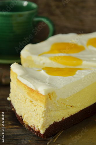 Cheesecake with cream and mango on a wooden background