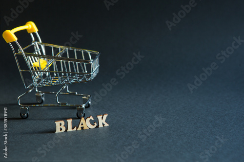 Shopping cart and the inscription "black" on a black background. Black Friday, discounts, sale, shopping, interest sign. Space for text