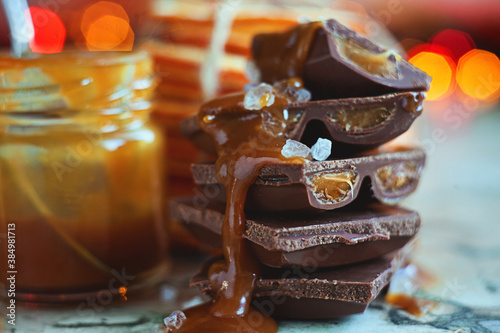 Macro chocolate pieces with caramel and sea salt against holiday background and dried oranges
