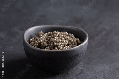 Sturgeon black caviar in black bowl on black background. Copy space. Close-up.