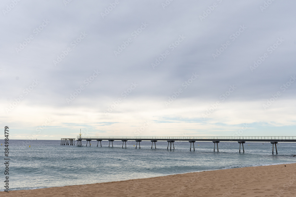 Landscape with walkway over beach and sea, a cloudy day, in Badalona, Catalonia, Spain, horizontal