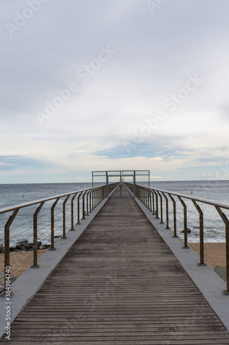 Perspective of footbridge over beach and sea  a cloudy day  in Badalona  Catalonia  Spain  in vertical