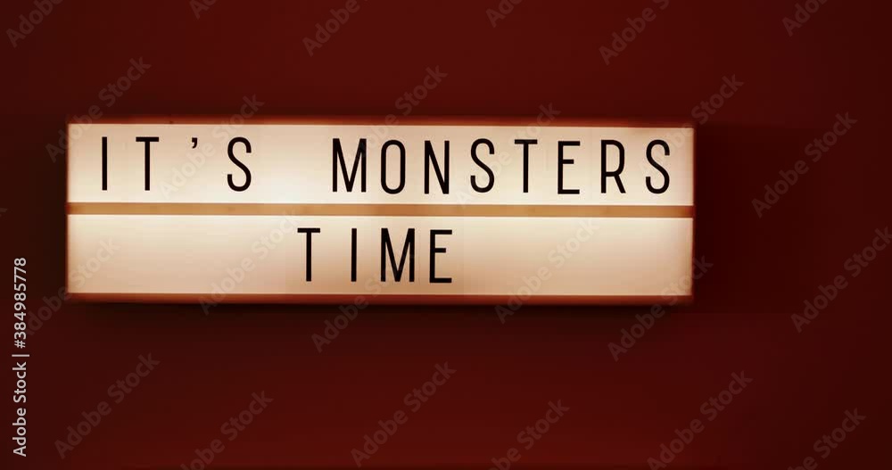 It's Monsters Time text displayed on a LED light box on the wall, red flicking light in the room, medium close-up, eye level 4k cinematic It's Monsters Time text displayed on a LED light box on the wall, red flicking light in the room, medium close-up, eye level 4k cinematic