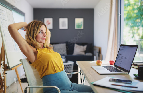 Mature woman working indoors in home office in container house in backyard, resting. photo