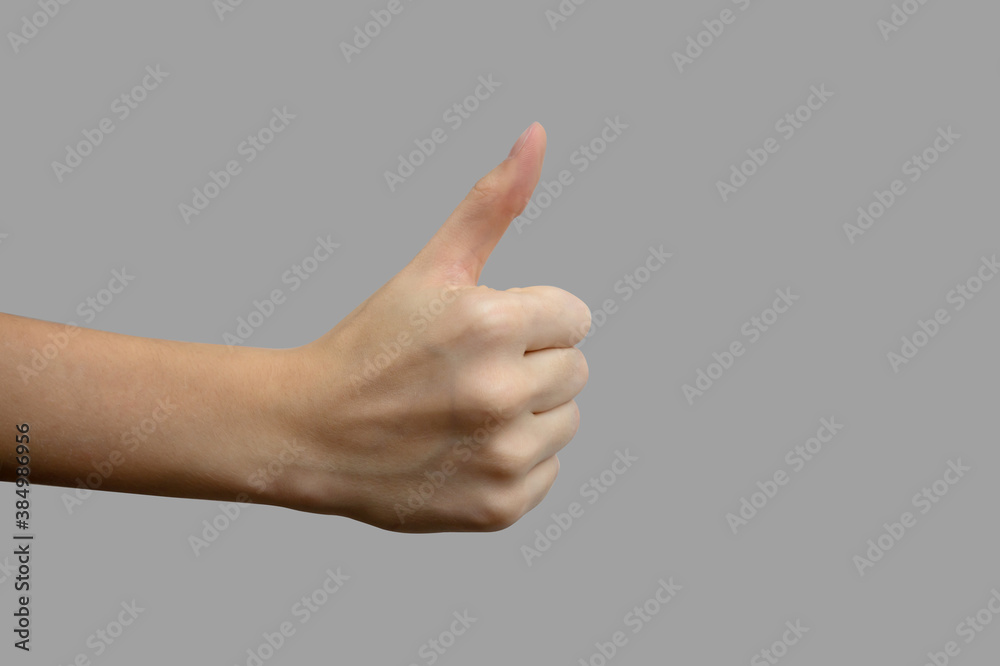 The sign of the thumb. Hand with white skin, showing the like sign, on a gray isolated background. Close-up, selective focus The sign of the thumb. Hand with white skin, showing the like sign, on a gray isolated background. Close-up, selective focus