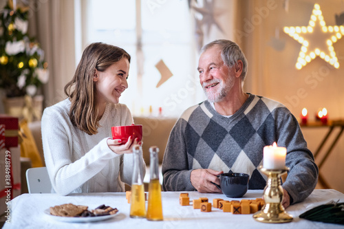 Young woman with grandfather indoors at home at Christmas, playing board games.