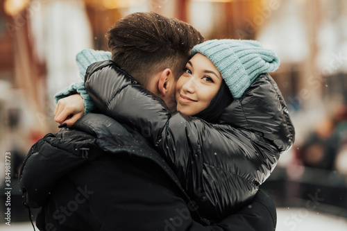 Close up portrait of a affectionate couple on winter holiday in the city. They hugging and happy girl are smiling. 