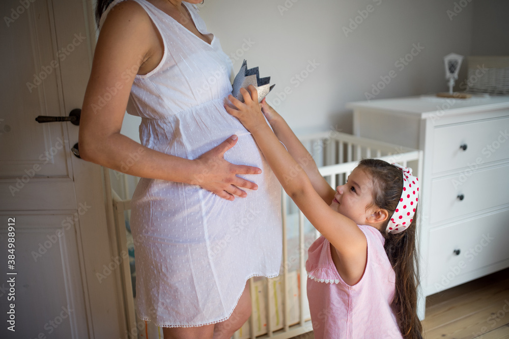 Small girl and unrecognizable pregnant mother indoors at home, playing. Small girl and unrecognizable pregnant mother indoors at home, playing.