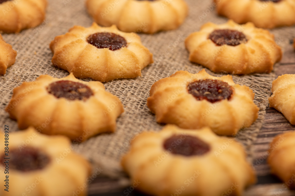Homemade pastry cookies with jam on a background of homespun fabric with a rough texture, close-up, selective focus.