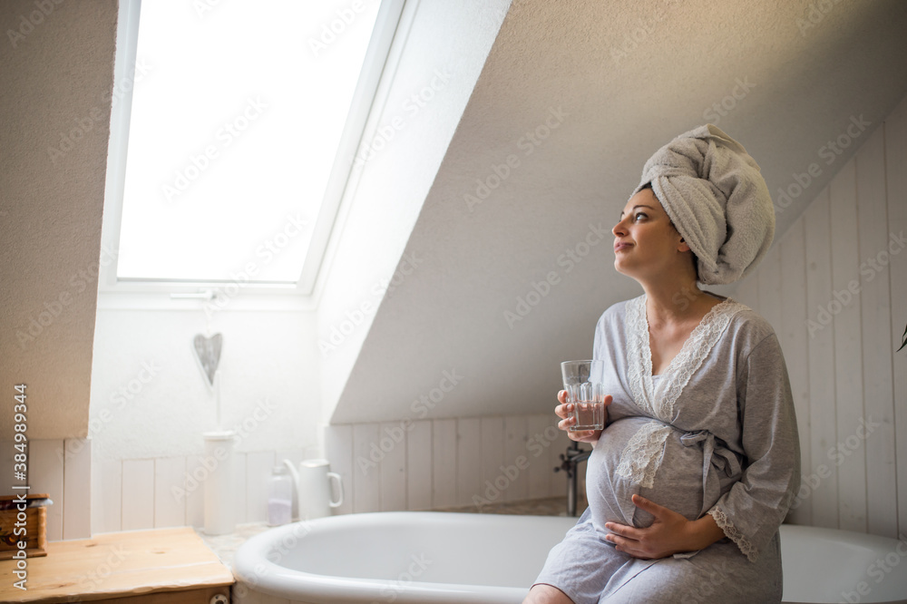 Portrait of happy pregnant woman indoors in bathroom at home, holding glass of water. Portrait of happy pregnant woman indoors in bathroom at home, holding glass of water.