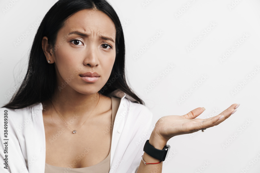 Beautiful unhappy asian woman holding copyspace and looking at camera Beautiful unhappy asian woman holding copyspace and looking at camera