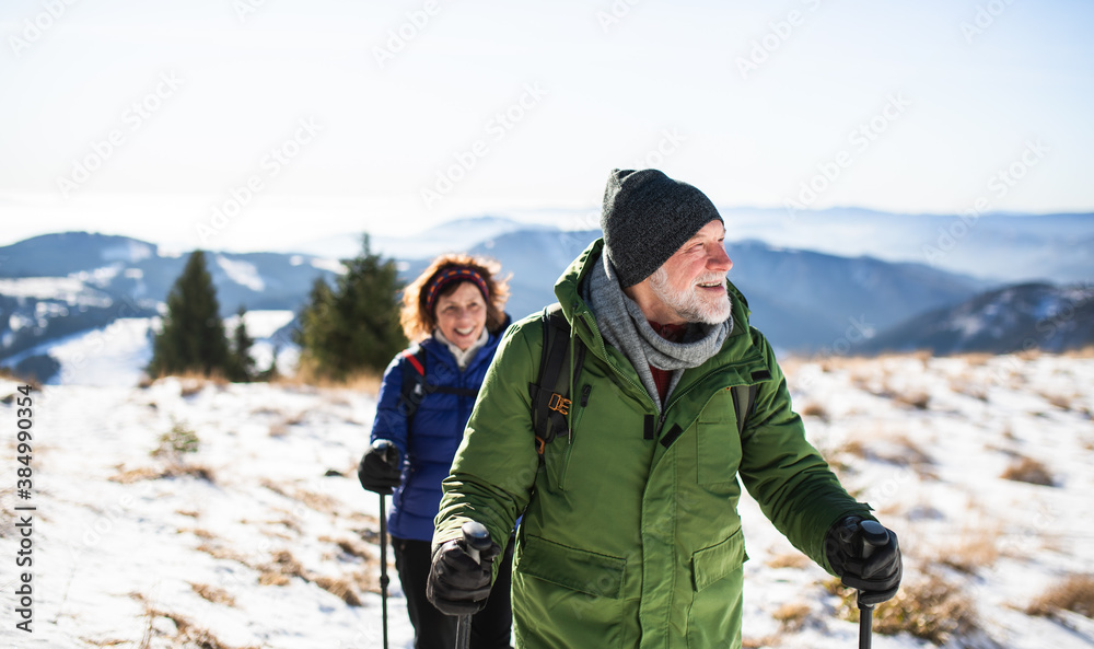 Φωτογραφία Senior couple with nordic walking poles hiking in snow-covered winter nature