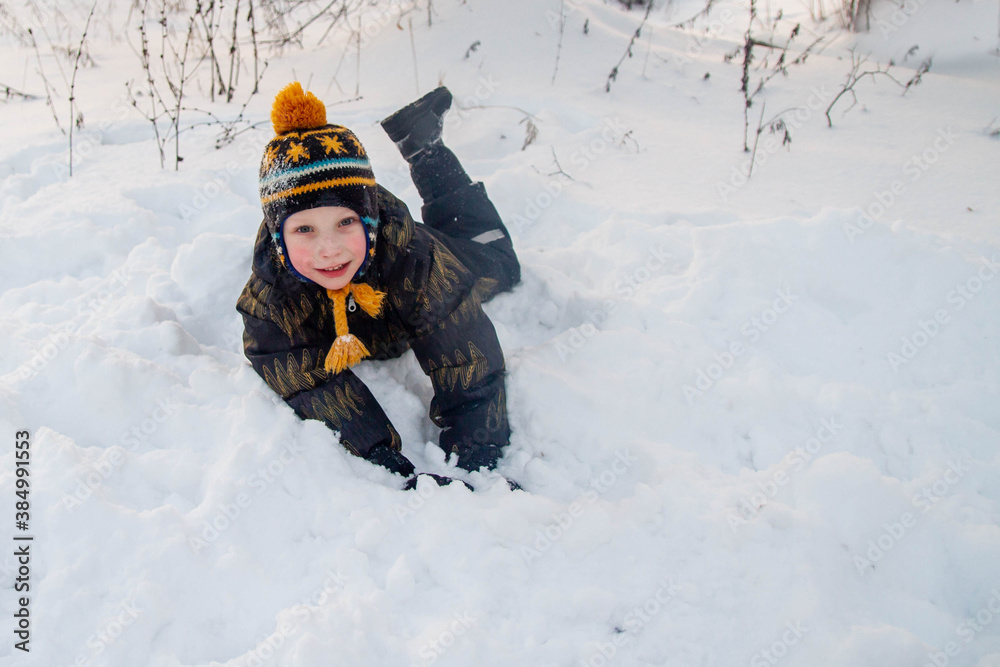 A European boy lies in the snow in winter. A European boy lies in the snow in winter.
