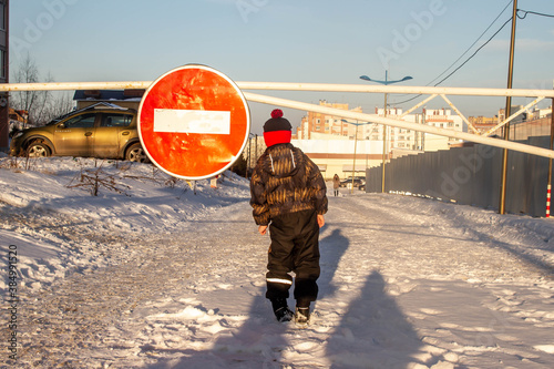 The boy stands in the winter on the road in front of the sign travel is prohibited. The boy is afraid to go further. photo