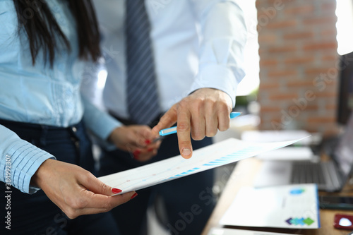 Man and woman colleagues examine document with schedule at workplace in company office close-up. Conducting business trainings concept.
