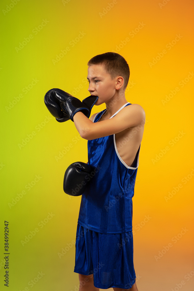 Emotions. Teenage professional boxer training in action, motion isolated on gradient background in neon light. Kicking, boxing. Concept of sport, movement, energy and dynamic, healthy lifestyle. Emotions. Teenage professional boxer training in action, motion isolated on gradient background in neon light. Kicking, boxing. Concept of sport, movement, energy and dynamic, healthy lifestyle.