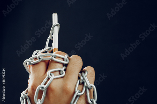 Male hand in metal chains holding cigarette