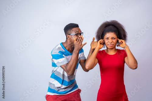 young african man yelling at a lady who covers her ears with her finger