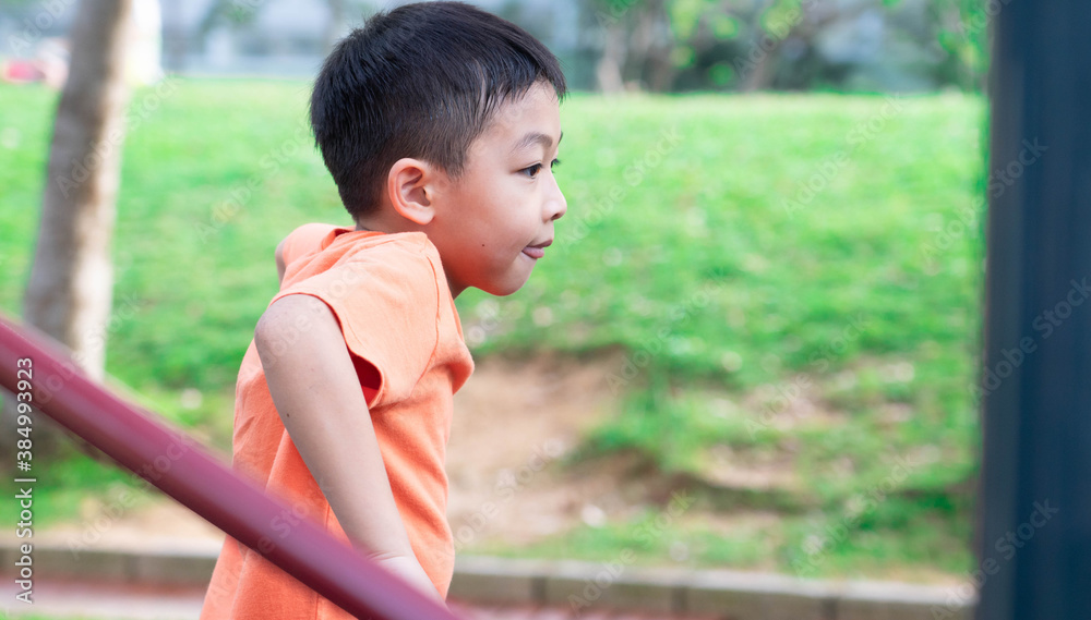 Obraz premium One sleepy and tired boy is playing in the park during Summer season.A child at the playground during the nice weather day.Outdoor activity after lock down at the public play area.