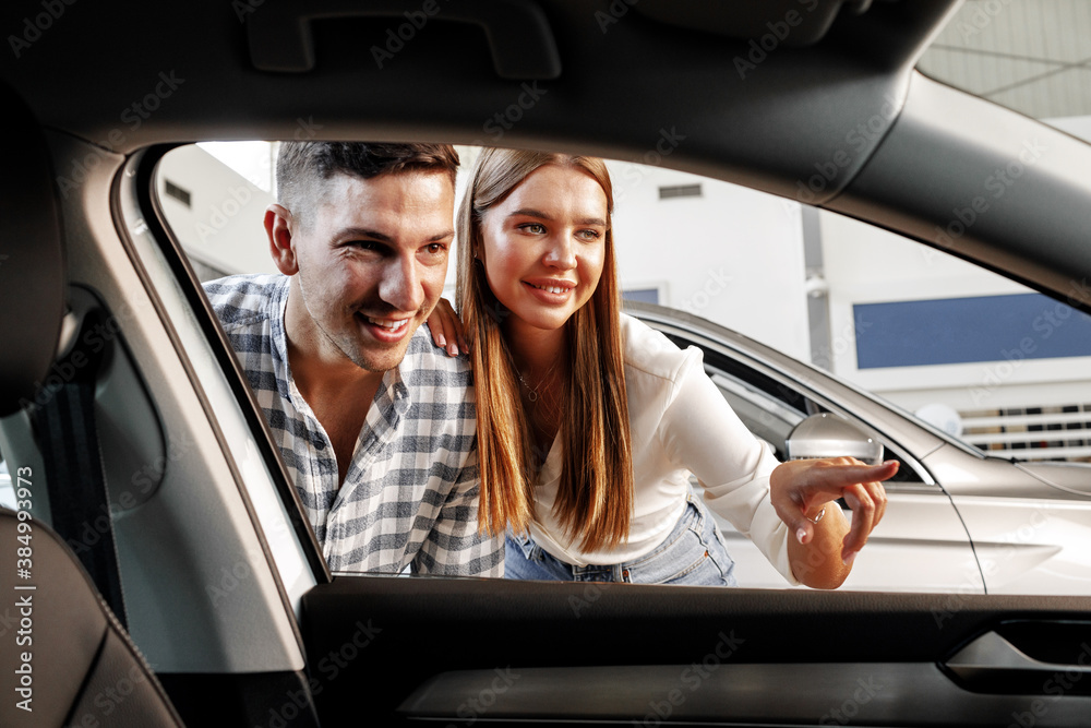 Young couple choosing their new car in a car shop