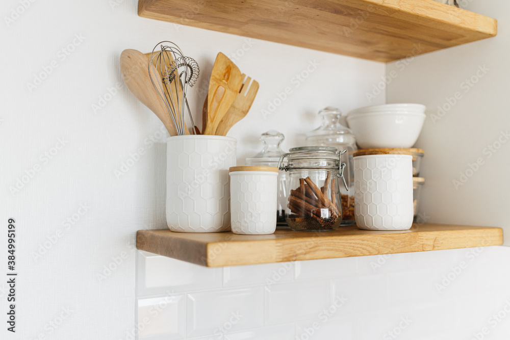 Kitchen shelves with various white ceramic and glass jars.