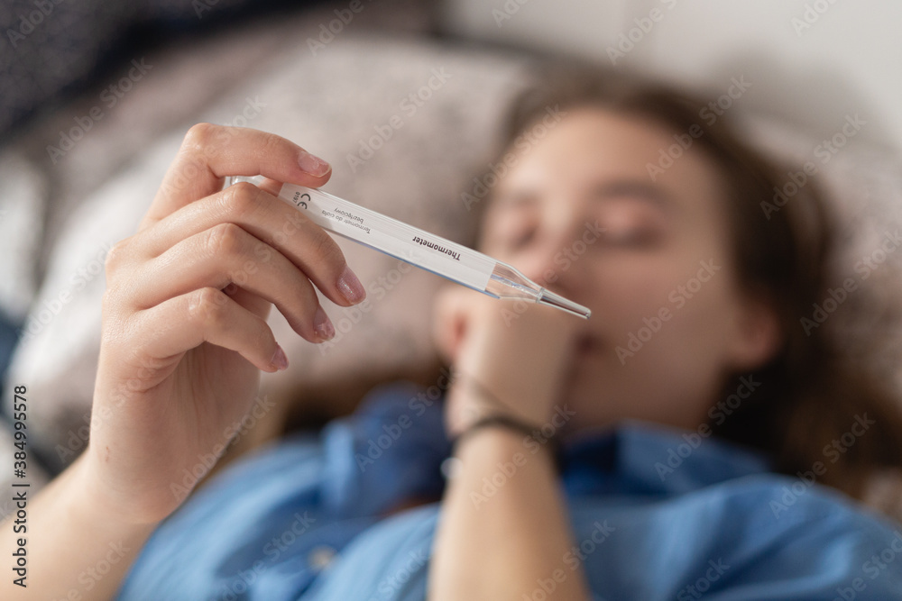 Woman holding medical thermometer while lying in bed and coughing. Coronavirus disease outbreak, Woman holding medical thermometer while lying in bed and coughing. Coronavirus disease outbreak,