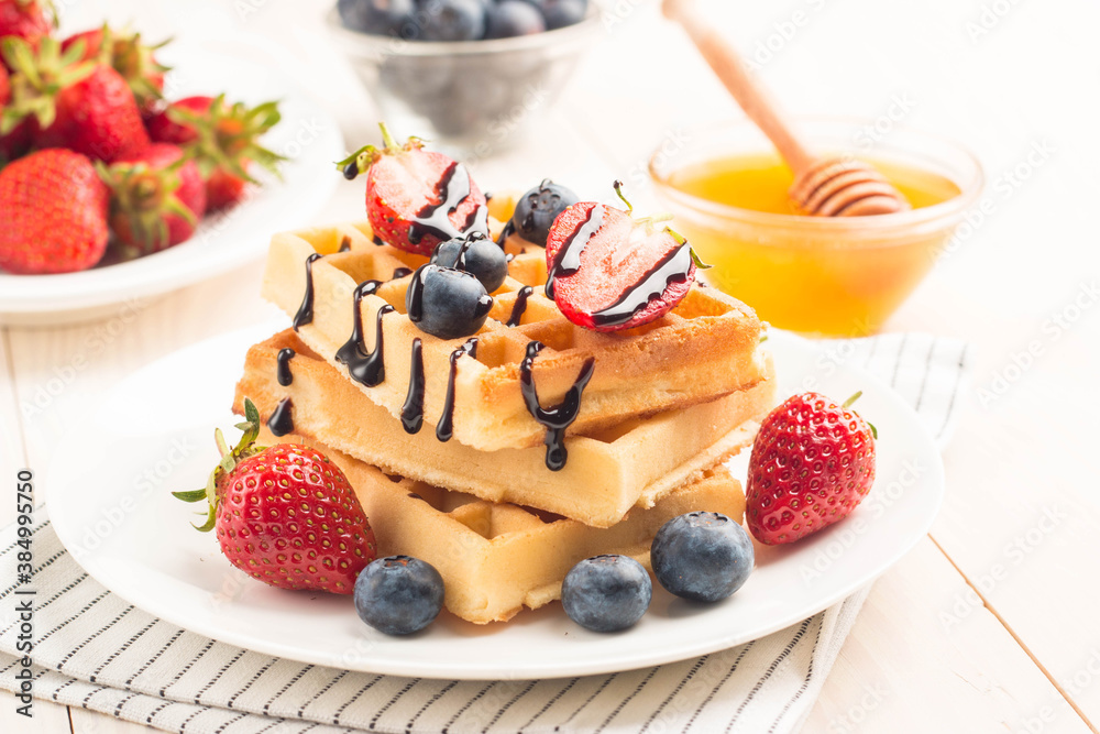 Fresh homemade food of berry Belgian waffles with honey, chocolate, strawberry, blueberry, maple syrup and cream. Healthy dessert breakfast concept with juice Fresh homemade food of berry Belgian waffles with honey, chocolate, strawberry, blueberry, maple syrup and cream. Healthy dessert breakfast concept with juice