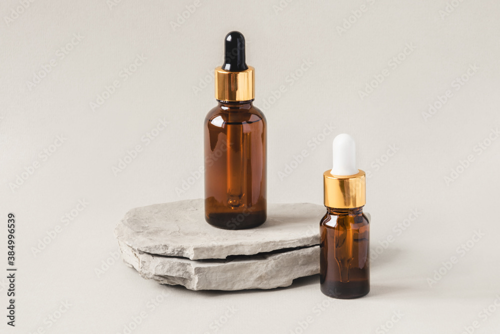 Two brown bottles of cosmetics on a natural gray background. Stone podium. Front view.