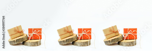 Two craft gifts on the wooden round cylinders shapes on the light background. Concept Christmas and New Year. Copy space. Banner.