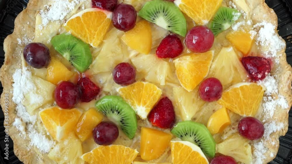 Top view of cake with fresh fruit and berries with cream rotates on tray. Holiday treat. Food dessert background. Bakery and pastry shop concept Top view of cake with fresh fruit and berries with cream rotates on tray. Holiday treat. Food dessert background. Bakery and pastry shop concept