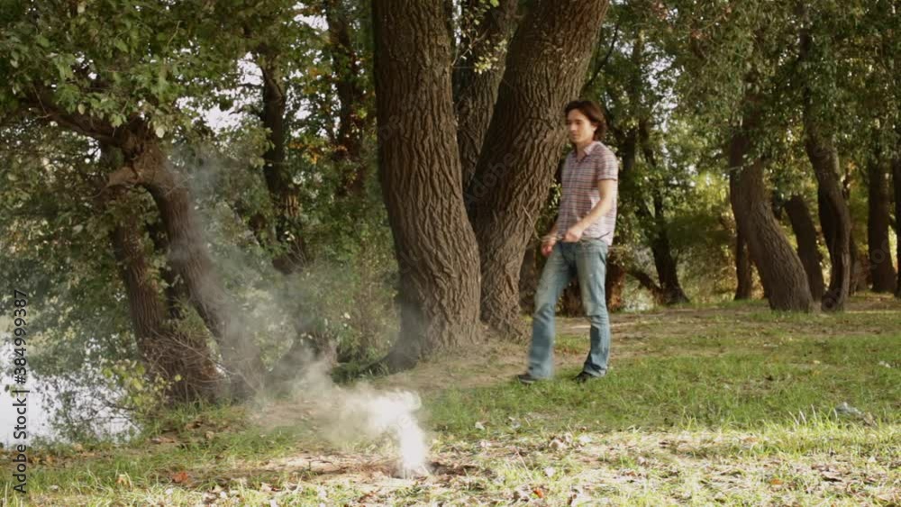 A man collects dry branches in the forest, lights a fire, rest in nature. A man collects dry branches in the forest, lights a fire, rest in nature.