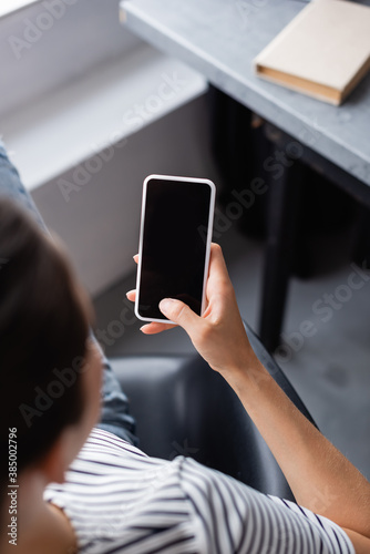 Overhead view of young woman using smartphone with blank screen at home