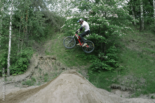 Professional biker jumping, doing tricks in the forest, cyclist training in the green woods. Training base in the forest, for cyclist and tricks, sports school