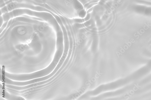 de-focused. Blurred desaturated transparent clear calm water surface texture with splashes and bubbles. Trendy abstract nature background. White-grey water waves in sunlight. Copy space.