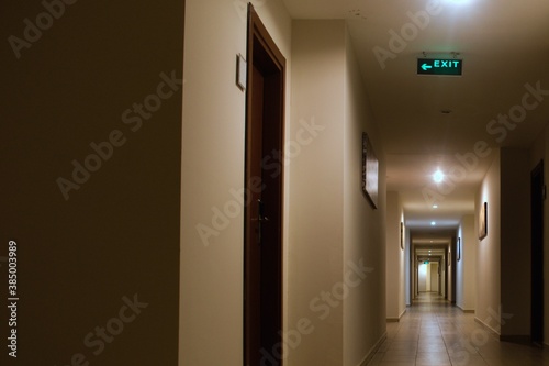 long interior corridor with many doors and exit signs