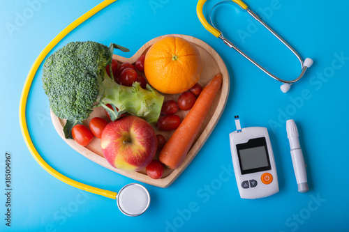 World diabetes day. National American diabetic awareness. Free Glucose Monitors on blue background. Yellow stethoscope check fruit on heart plate. Healthcare and medical concept