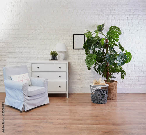 Fototapeta Naklejka Na Ścianę i Meble -  Decorative white cabinet and blue armchair, vase of plant and blanket style, brick wall background.