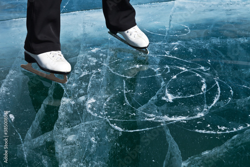 Ice skating on a frozen lake. Top view of the beautiful transparent ice of the frozen Baikal Lake. Winter travel and active rest. Focus on the ice surface, skates in motion out of focus