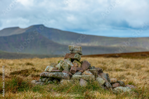 A close up of a small summit cairn (Waun Rydd) in the Welch mountain with other summit in the backgound under a grey stormy sky photo