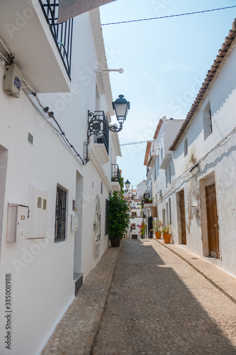 Beautiful narrow street in Altea, Costa Blanca, Valencian Community, Spain. Historical center. Stone stairs going up. Vertical shot. White architecture. Nobody in the street. 