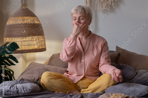 Senior woman practicing yoga at home, making Alternate Nostril Breathing exercise, nadi shodhana pranayama photo