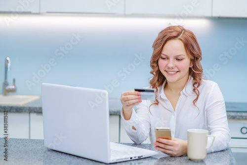Young woman holding credit card and using laptop computer. Businesswoman or entrepreneur working at home. Online shopping, e-commerce, internet banking, spending money, working from home concept