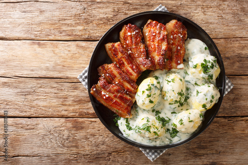 Crispy pork with parsley sauce (stegt flæsk med persillesovs) is widely considered Denmark's national dish closeup in the plate on the table. Horizontal top view from above