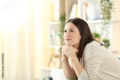 Pensive woman looks up on a sofa at home Free Download Pensive woman looks up on a sofa at home - GFXLoad